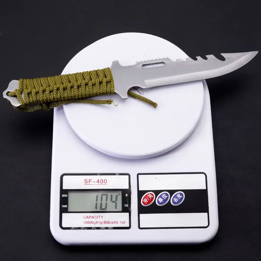 Knife with green paracord on a digital scale displaying weight
