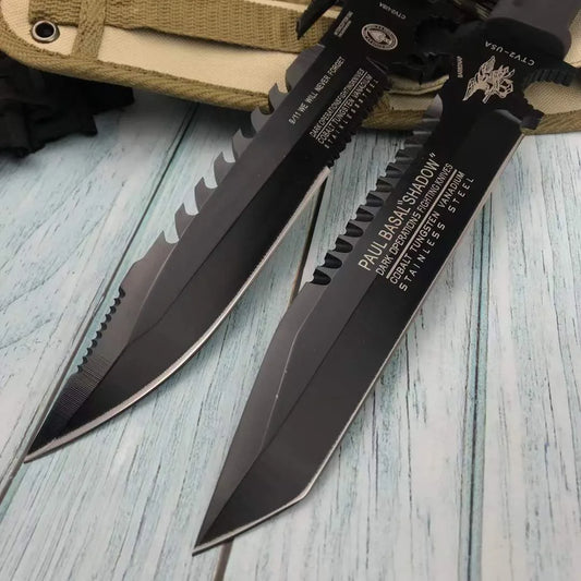 Black tactical knife with a saw blade on a wooden surface