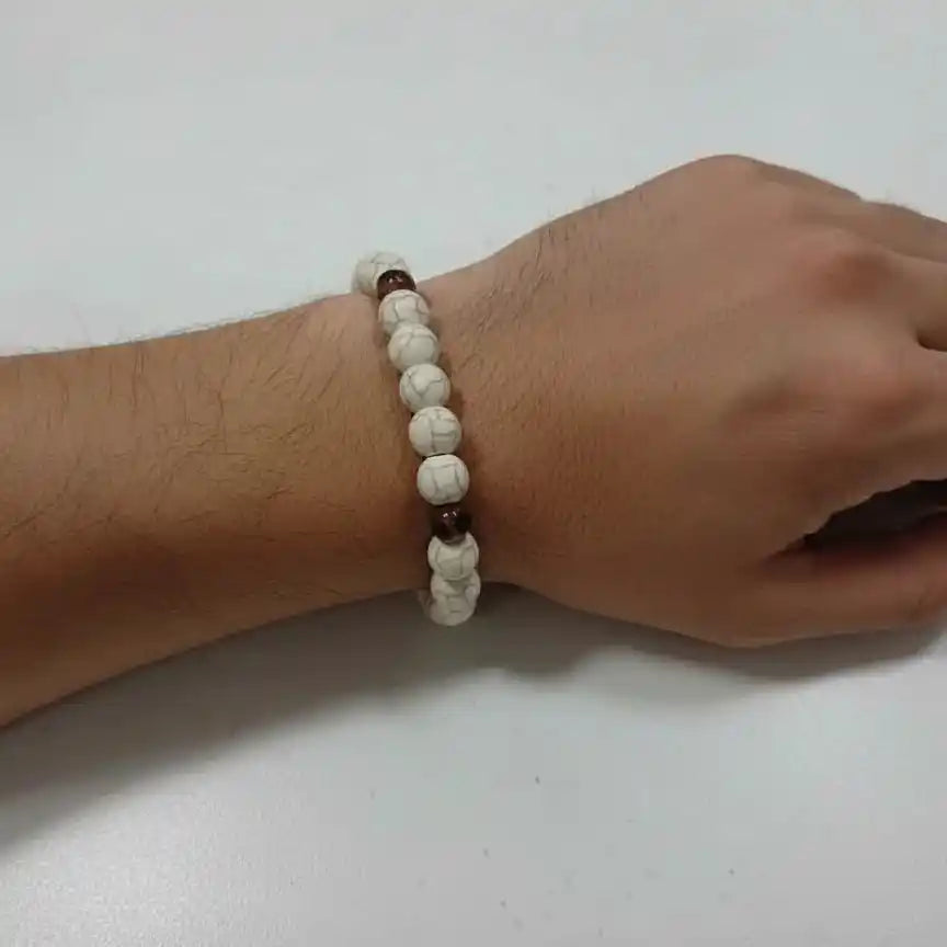 A stretchable white howlite bead bracelet on a white surface.
