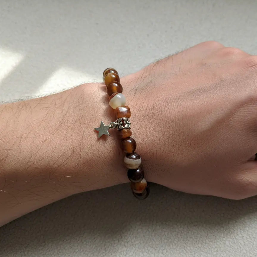 Close-up view of a brown banded agate stretch bracelet with mixed light and dark polished stone beads.