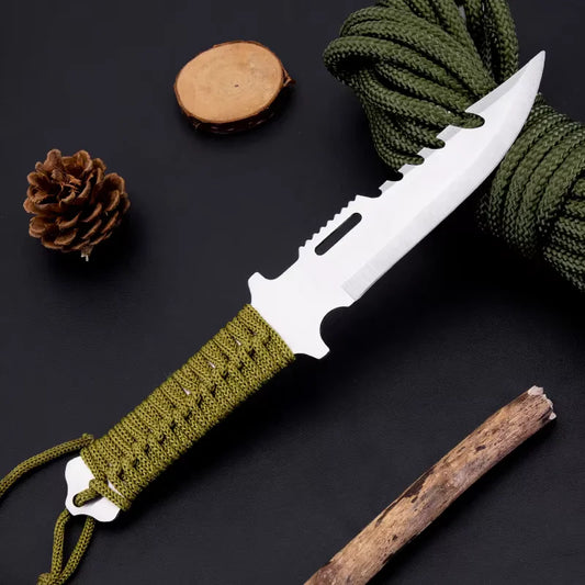 Knife with green handle and cord on a dark surface with pine cone and stick